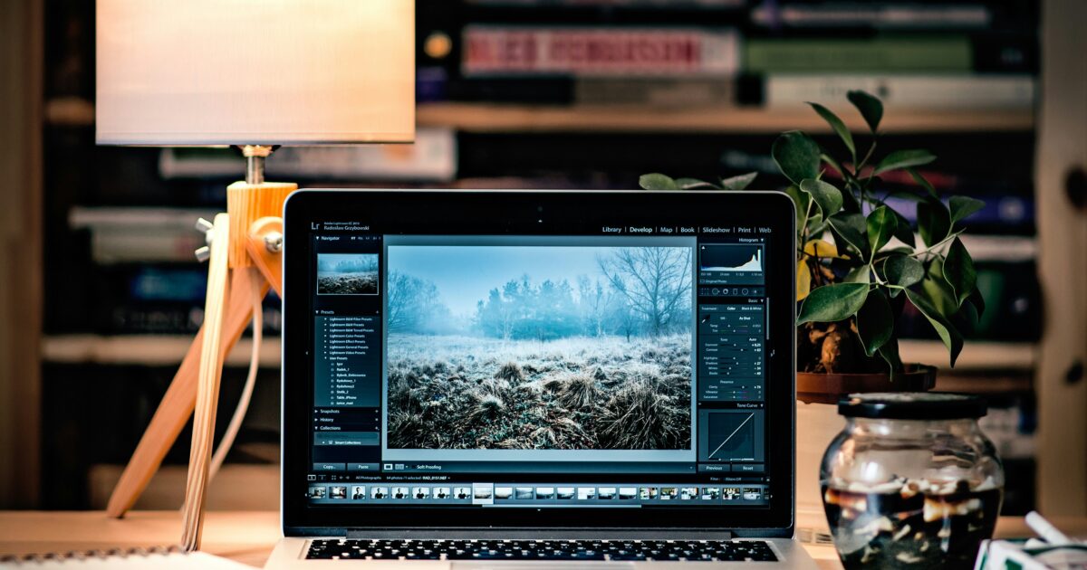 デスクに置かれたノートパソコンで写真編集ソフトを使用しているクリエイティブな作業空間