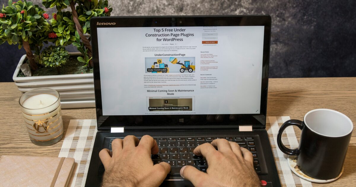WordPressプラグインの紹介記事を表示しながら作業するノートパソコンと男性の手元
