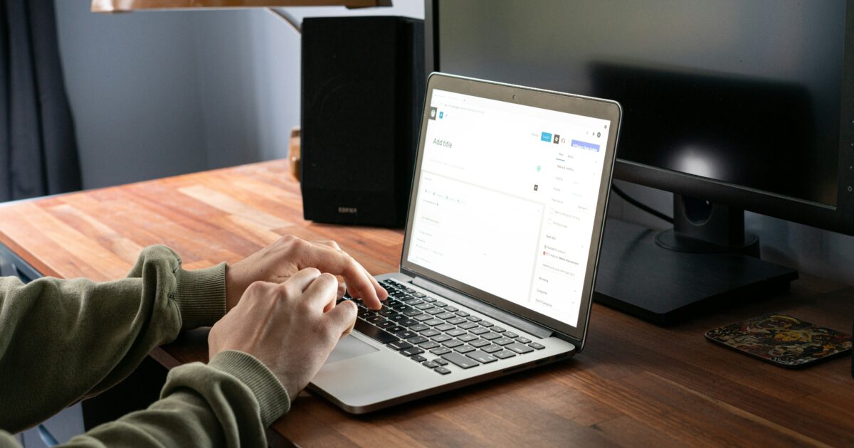WordPressの投稿画面を操作しているノートパソコンと木製デスクのワークスペース